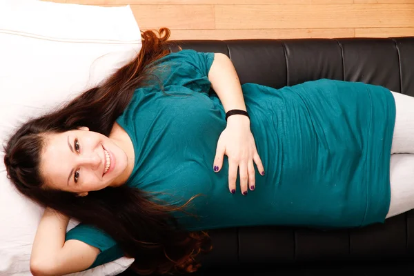 Junge Frau entspannt sich auf Sofa — Stockfoto